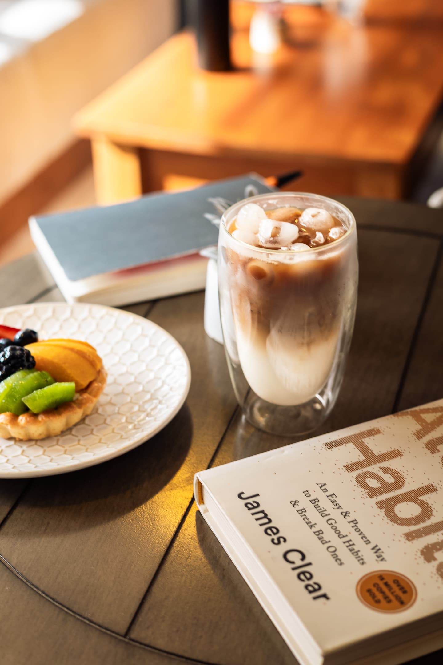 An iced coffee catching afternoon light on a dark café table.